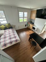 Studio mit Bett, Küche, TV und Schrank mit Sitzgelegenheit. 4 Fenster inkl. Storen