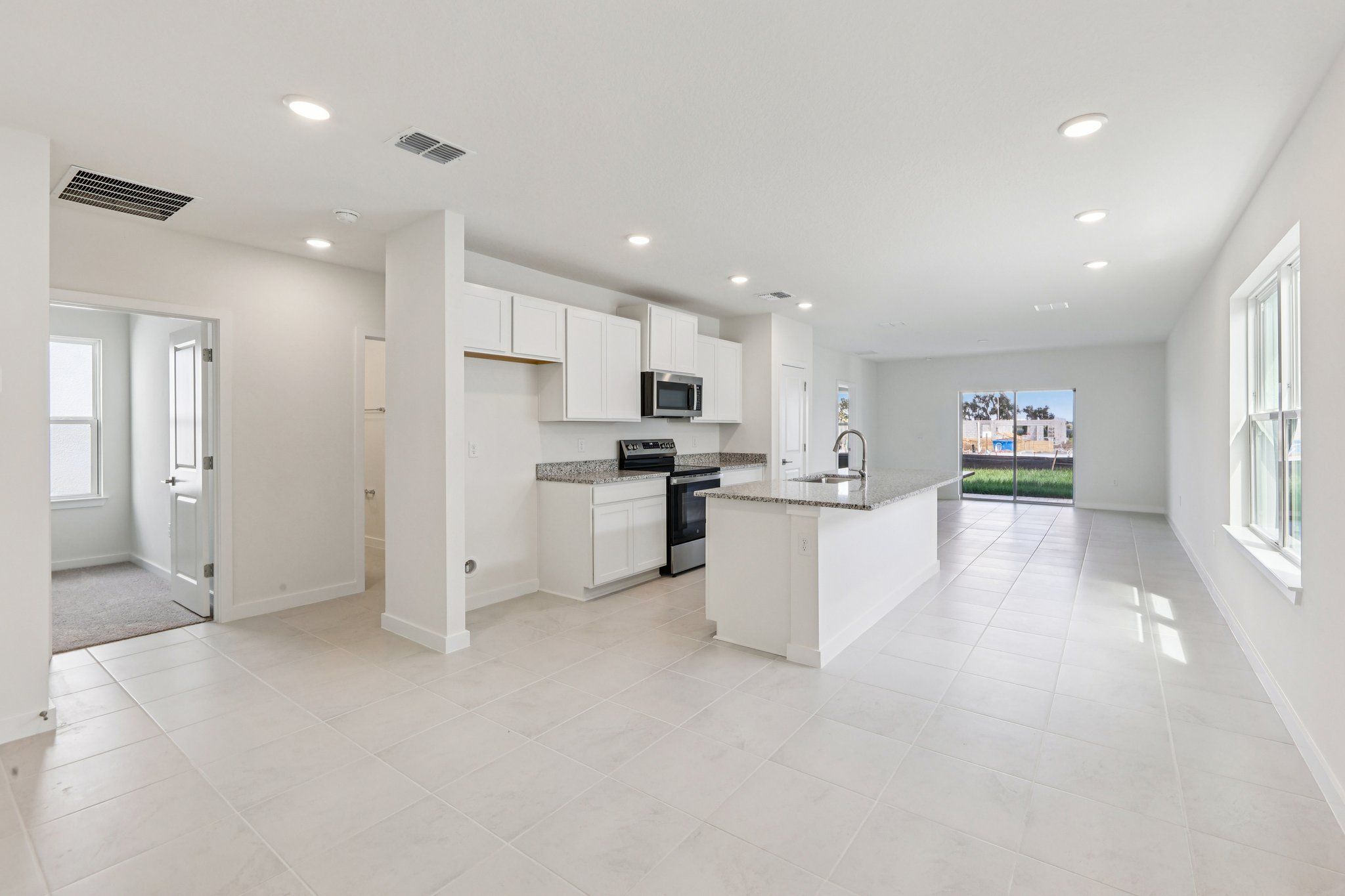 Open kitchen with an island, adjoining tiled living space and sliding glass doors visible in the same frame.