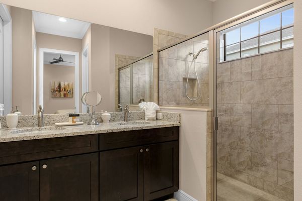 The en suite bathroom has a glass walk-in shower and granite his and hers sink