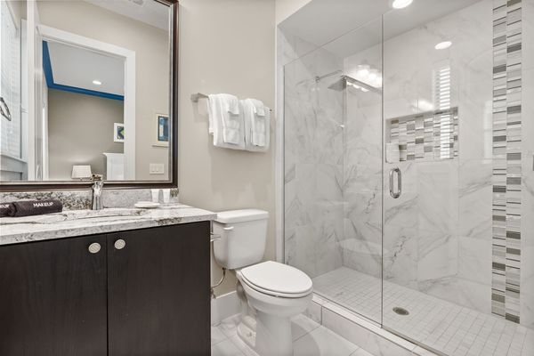 This bathroom is complete with a glass walk-in shower and granite countertops