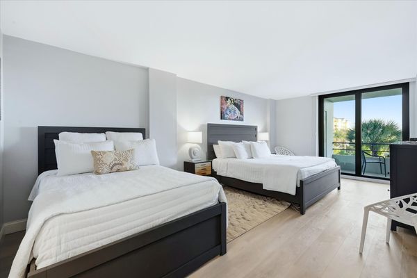 Bedroom 1 with one king bed, one queen bed, balcony access, attached bathroom, and 55-inch Smart TV