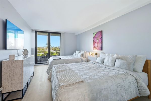 Bedroom 2 with two queen beds, balcony access, and 55-inch Smart TV