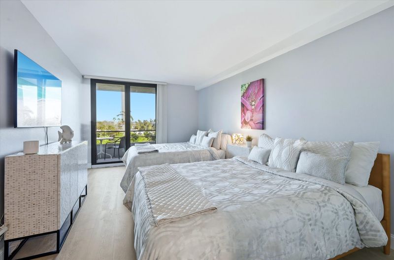 Bedroom 2 with two queen beds, balcony access, and 55-inch Smart TV