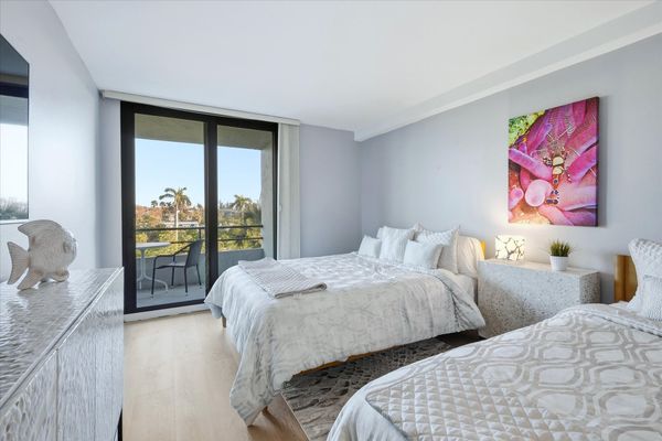 Bedroom 2 with two queen beds, balcony access, and 55-inch Smart TV