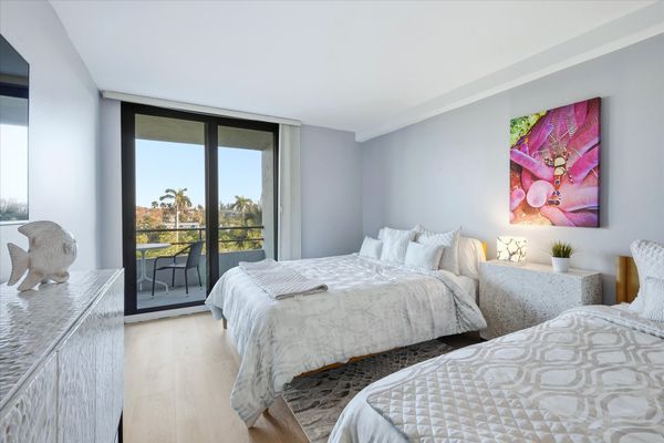Bedroom 2 with two queen beds, balcony access, and 55-inch Smart TV