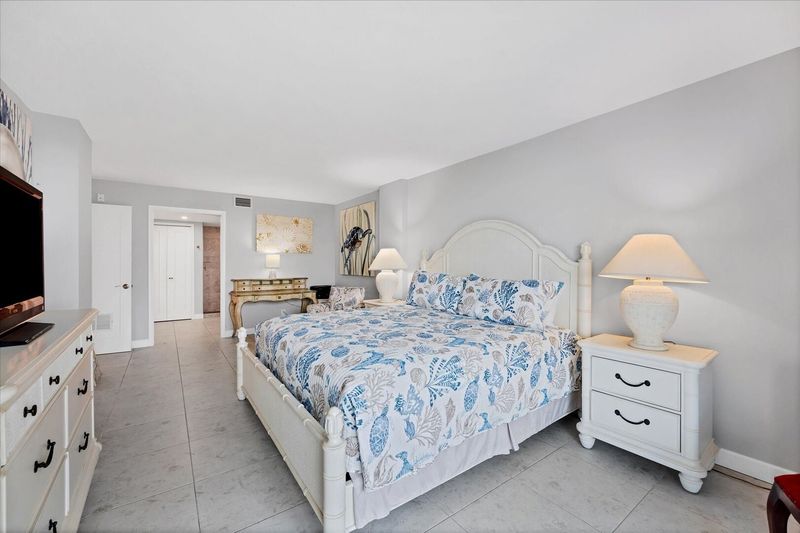 Primary bedroom with king bed, desk, en suite, balcony access, and 43-inch Smart TV