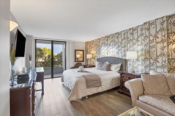 Primary bedroom with king bed, 55-inch Smart TV. sitting area, attached bathroom and balcony access