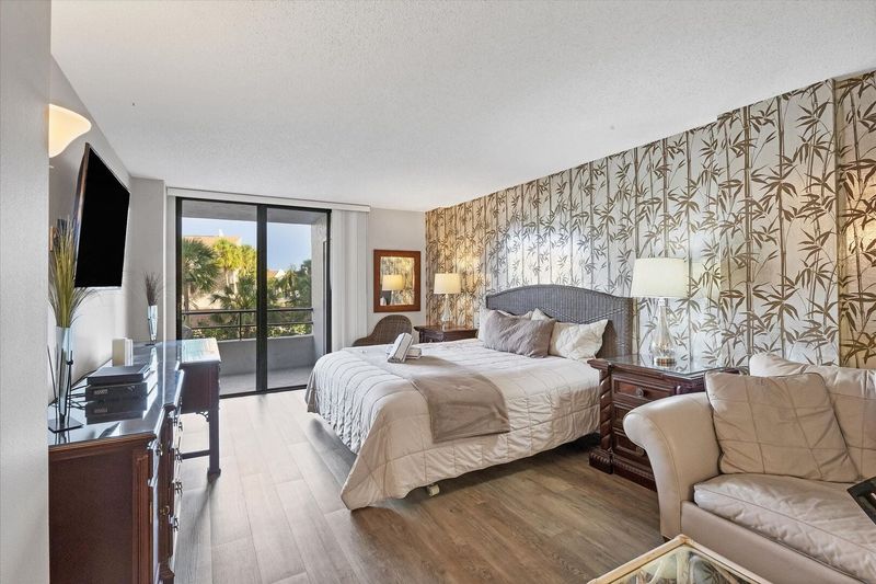 Primary bedroom with king bed, 55-inch Smart TV. sitting area, attached bathroom and balcony access