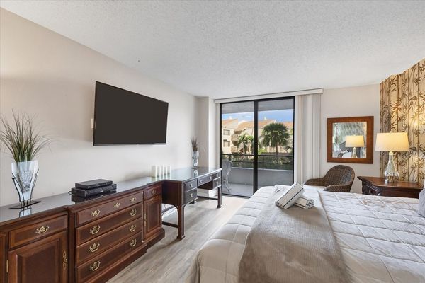 Primary bedroom with king bed, 55-inch Smart TV. sitting area, attached bathroom and balcony access