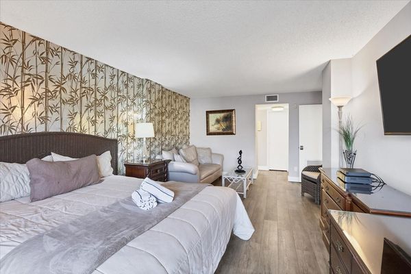 Primary bedroom with king bed, 55-inch Smart TV. sitting area, attached bathroom and balcony access