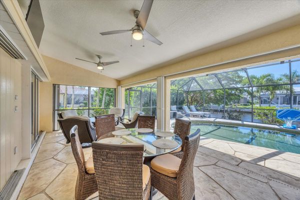 Amazing outdoor living space with dining table, sparkling pool, grill area with bar, and 55-inch Smart TV