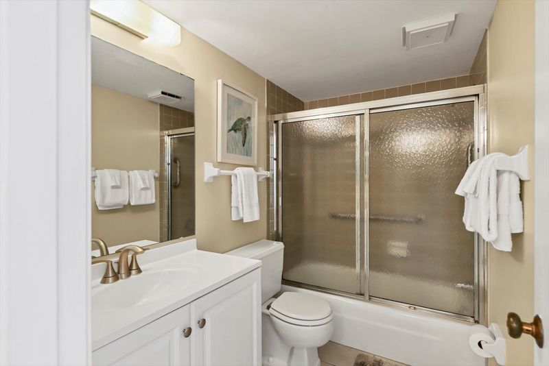 Bedroom 1's attached bathroom with shower/tub combo and two vanities