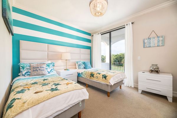 This coastal-themed bedroom on the third floor offers two twin beds with a shared balcony and bathroom