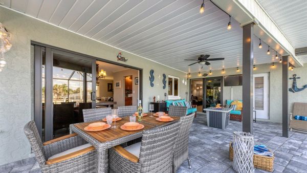 Incredible outdoor living space with dining table, comfortable seating and fire table overlooking the pool and canal beyond