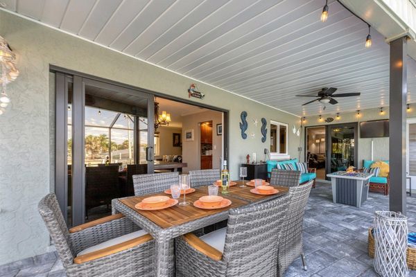 Incredible outdoor living space with dining table, comfortable seating and fire table overlooking the pool and canal beyond
