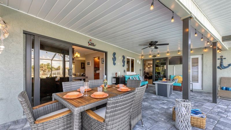 Incredible outdoor living space with dining table, comfortable seating and fire table overlooking the pool and canal beyond