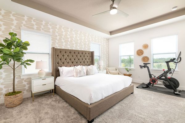 This second-floor master suite offers a king-sized bed, Peloton bike, private balcony, and en suite bathroom