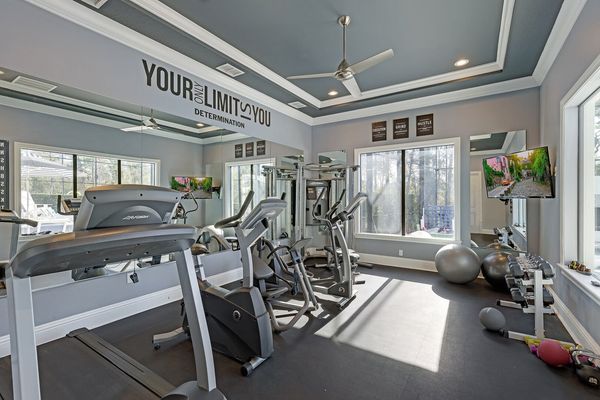 A fitness room with G7 home gym, treadmill, elliptical, bike, free weights and pool views