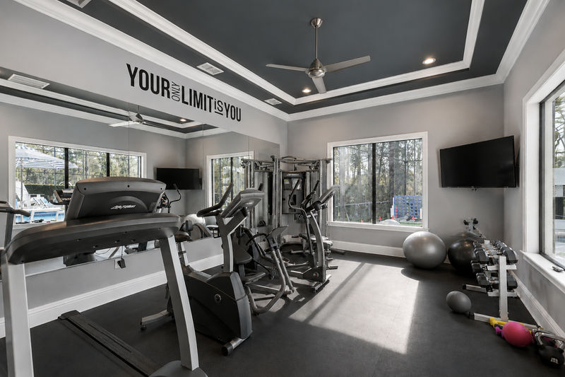 A fitness room with G7 home gym, treadmill, elliptical, bike, free weights and pool views