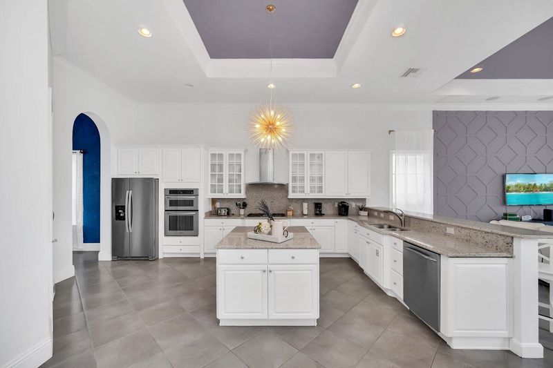 The open kitchen features modern appliances like a sleek 2-door fridge, oven, coffee maker, and more. With a central table at your disposal, meal preparation becomes a seamless and enjoyable experience.