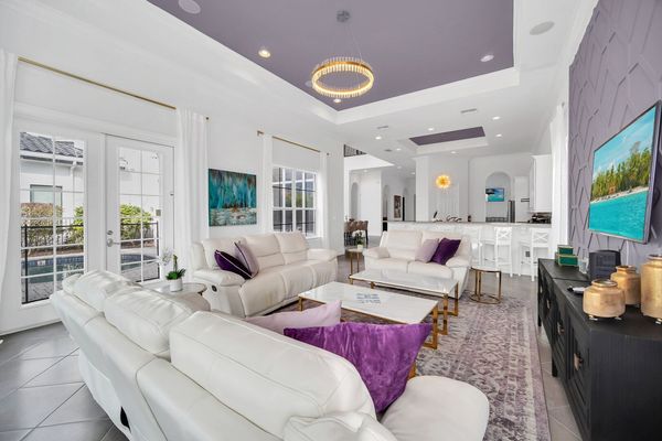 Step into our living room adorned in calming shades of purple, with a glass door beckoning you towards the patio and pool area.