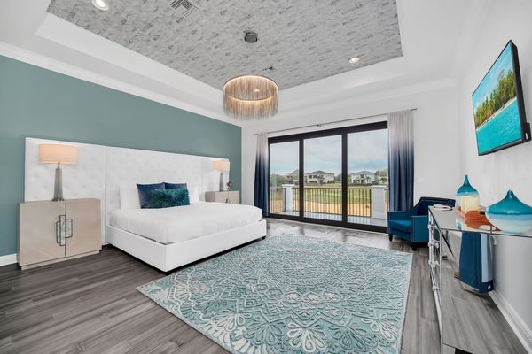Master bedroom on the second floor, boasting a grand King bed, expansive windows flooding the space with natural light.