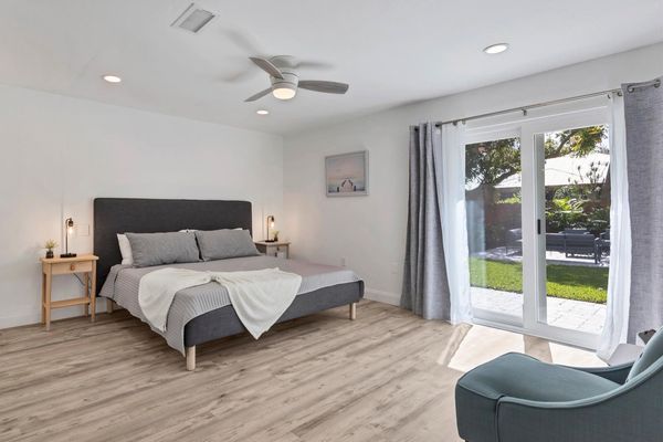 Primary bedroom with king bed, attached bathroom, access to backyard, and 50-inch Smart TV