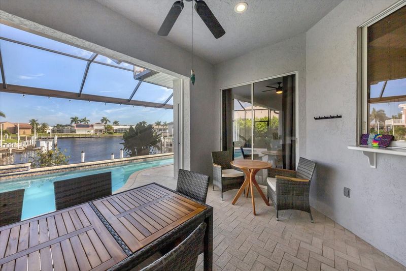 Spacious outdoor area with dining table overlooking the sparkling pool and canal beyond