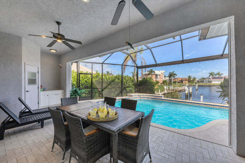 Spacious outdoor area with dining table overlooking the sparkling pool and canal beyond