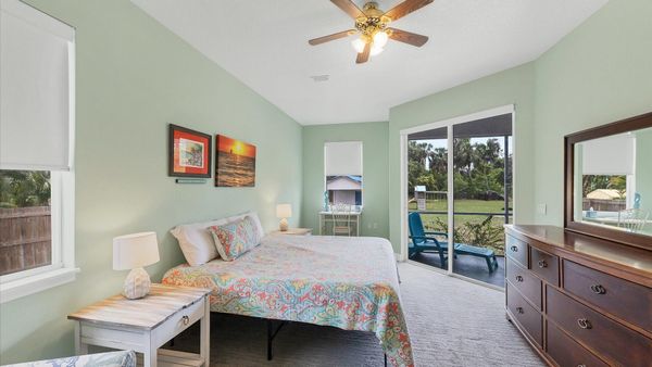 primary bedroom featuring king bed, workspace, and access to lanai