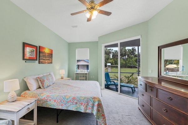 primary bedroom featuring king bed, workspace, and access to lanai