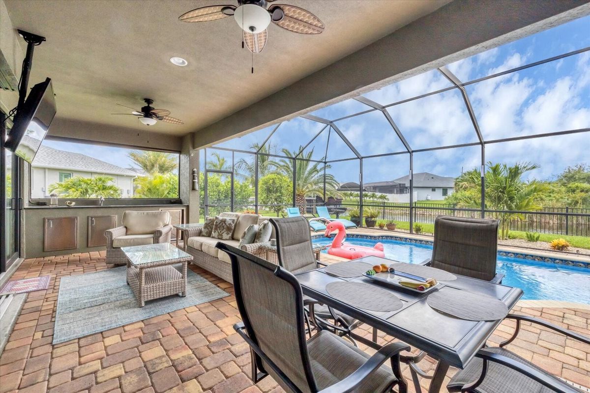 Perfect outdoor space overlooking the pool and canal. Lanai features outdoor kitchen, dining & seating areas, sun loungers, 55-inch Smart TV