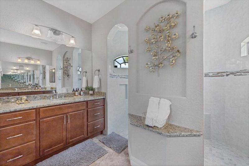 Primary bedroom en suite featuring large walk-in shower & double vanities