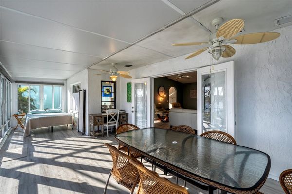 Sunroom overlooking pool and canal with outdoor dining, desk, and queen bed. Nook with queen  bed has a room divider for privacy