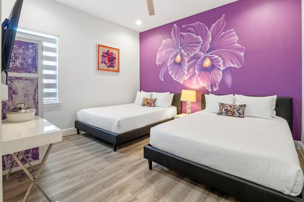 Discover a dreamy escape in our bedroom adorned in a calming shade of purple, complemented by the enchanting presence of a beautiful flower painting.