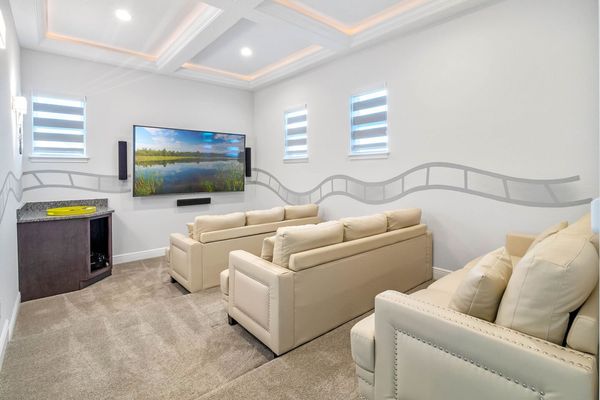 The theater boasts three comfortable sofas, providing seating for up to nine guests, all positioned perfectly for enjoying the immersive experience of a 120-inch smart TV and surround sound system.
