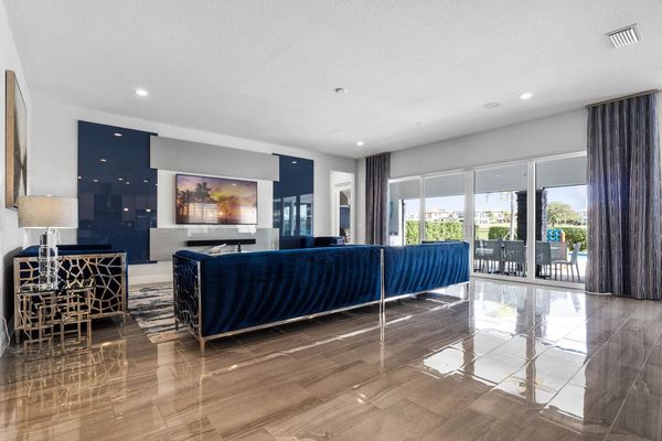 Enter our living room, adorned in calming shades of blue, with a glass door inviting you to the patio and pool area, flooding the space with natural light and promising serene moments of relaxation.