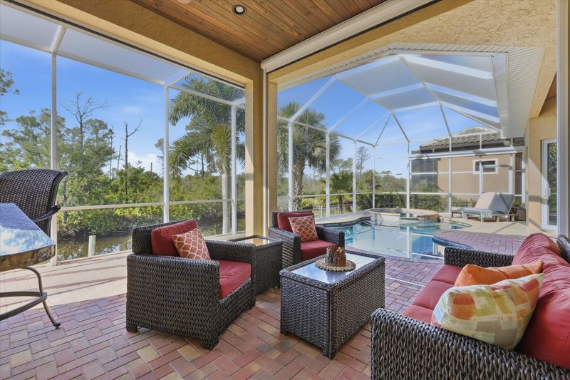 Large outdoor living space overlooking canal and nature preserve. Lanai features ample seating, outdoor kitchen, bar, 65-inch Smart TV, sparkling private pool & spa, and remote controlled privacy screens