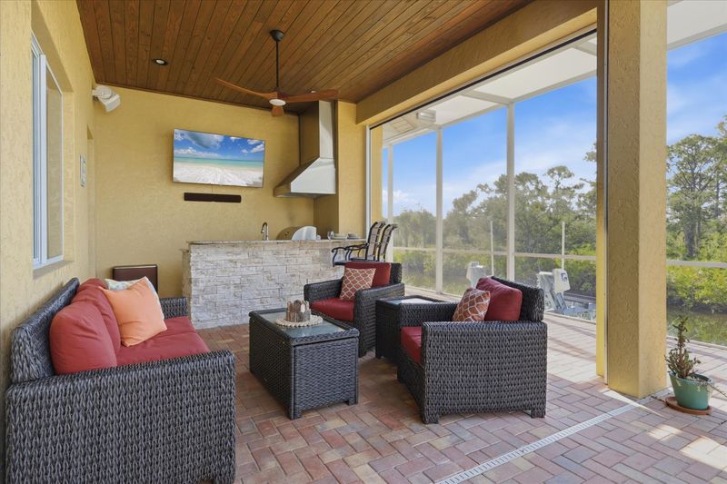 Large outdoor living space overlooking canal and nature preserve. Lanai features ample seating, outdoor kitchen, bar, 65-inch Smart TV, sparkling private pool & spa, and remote controlled privacy screens