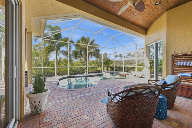 Large outdoor living space overlooking canal and nature preserve. Lanai features ample seating, outdoor kitchen, bar, 65-inch Smart TV, sparkling private pool & spa, and remote controlled privacy screens