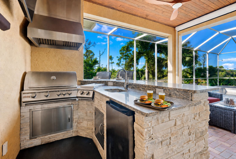 Large outdoor living space overlooking canal and nature preserve. Lanai features ample seating, outdoor kitchen, bar, 65-inch Smart TV, sparkling private pool & spa, and remote controlled privacy screens