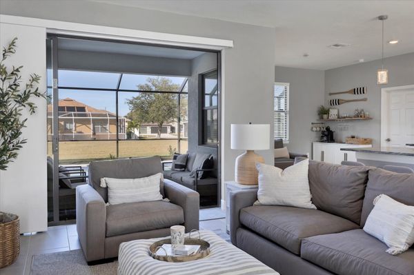 Living room overlooks the pool and features comfy seating and a 55" Smart TV