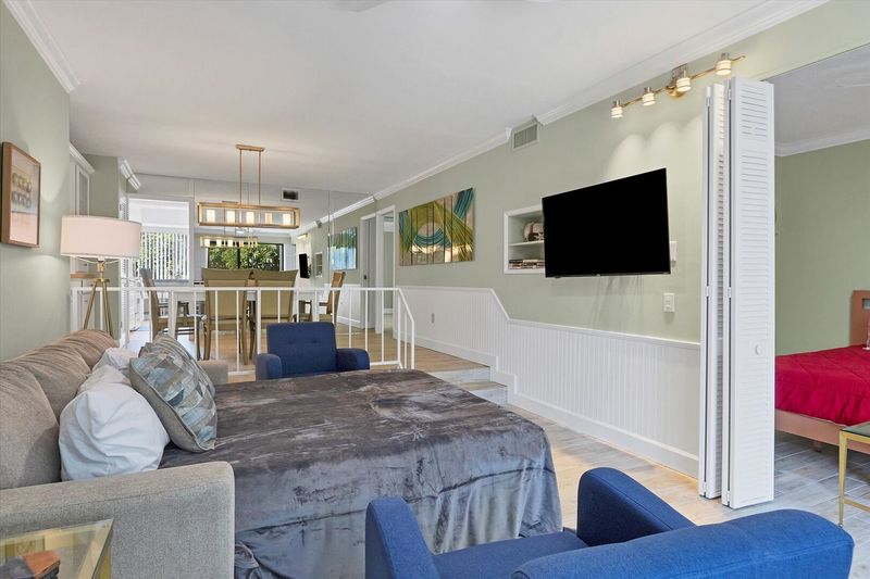 Living room with 55-inch TV, balcony access, and queen sofa bed