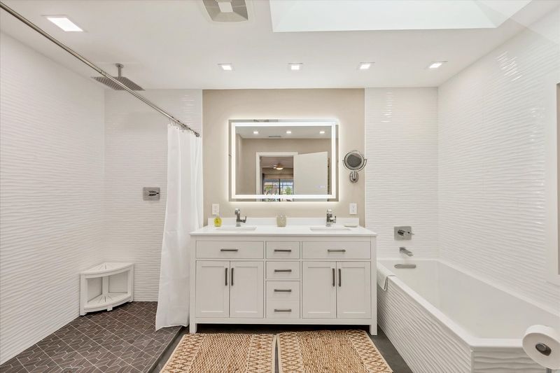 Primary Bathroom with large walk-in shower, double vanities, and bath tub