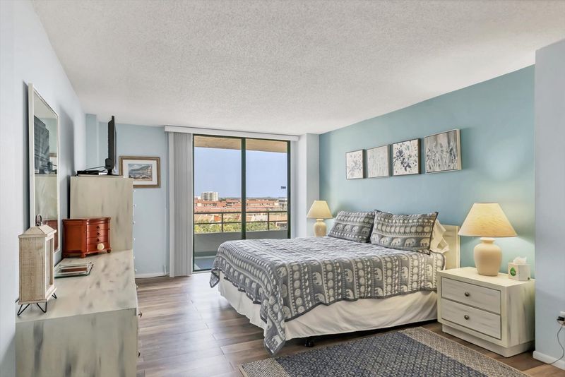 Primary Bedroom with king bed, en suite, balcony access, and a 32" TV
