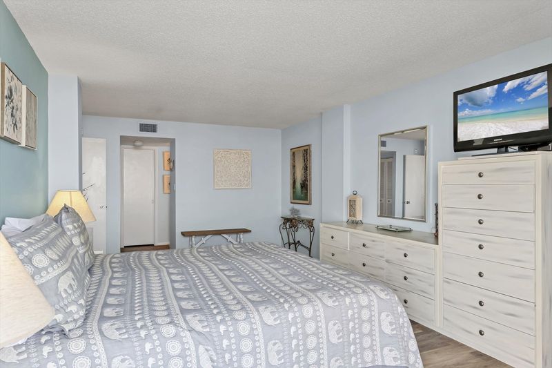 Primary Bedroom with king bed, en suite, balcony access, and a 32" TV