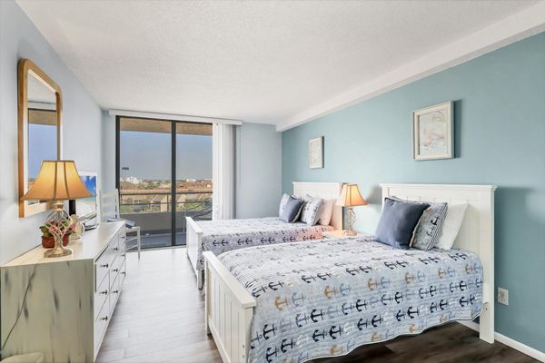 Guest Bedroom with one Queen Bed, one twin bed, balcony access, and a 32" TV