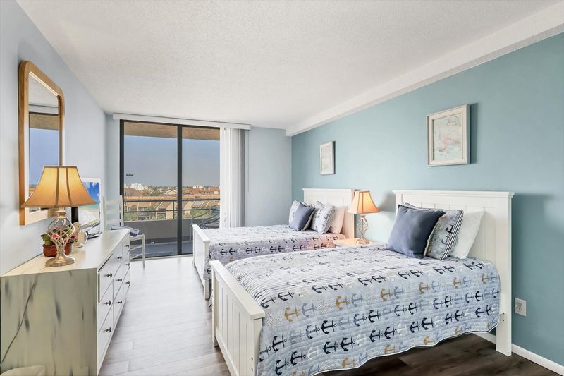 Guest Bedroom with one Queen Bed, one twin bed, balcony access, and a 32" TV