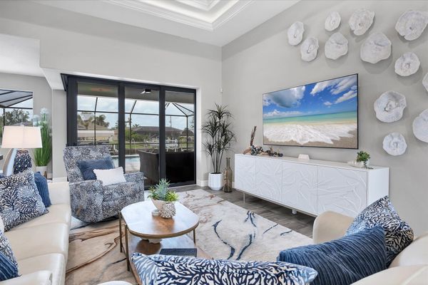 Living room overlooking the sparkling pool and canal beyond. Living room features lots of comfy seating and 75-inch Smart TV