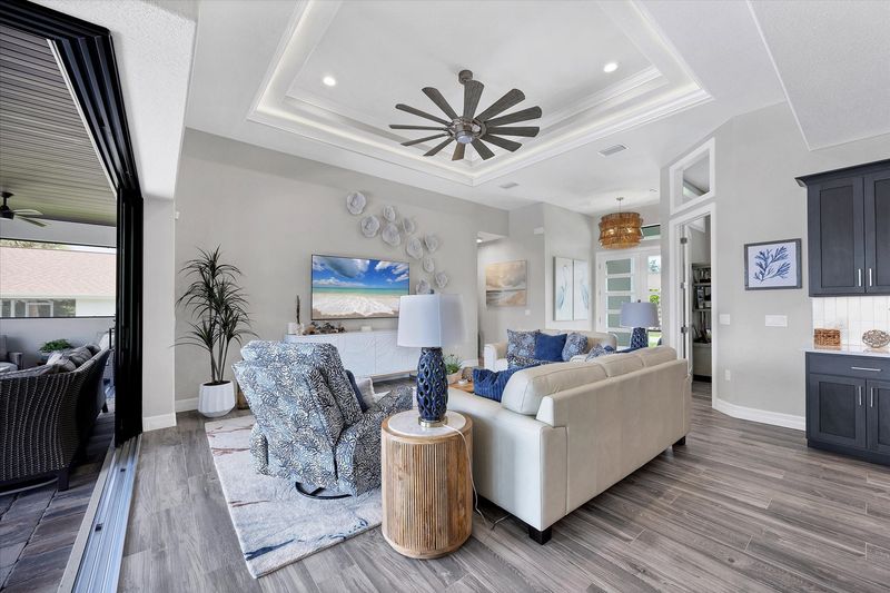 Living room overlooking the sparkling pool and canal beyond. Living room features lots of comfy seating and 75-inch Smart TV